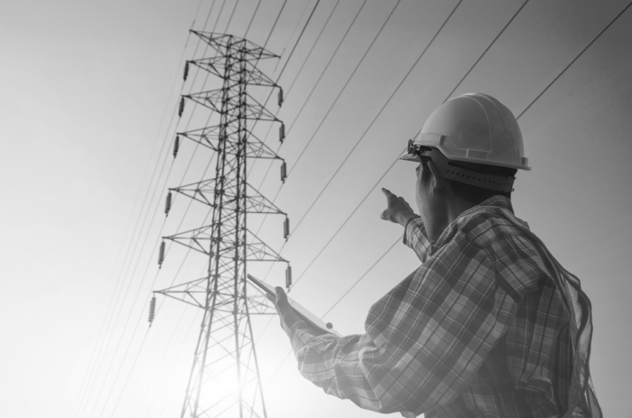 Engineer in the field points to a pylon while holding a tablet